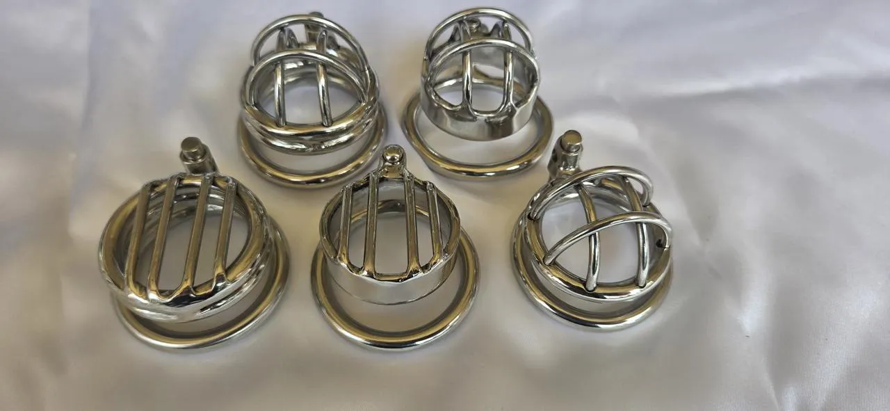 Five short stainless steel chastity cages photographed front-on with their base rings