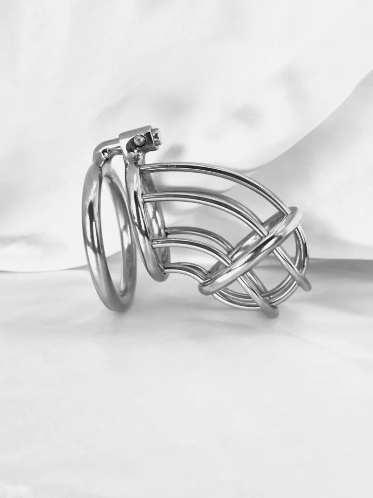 Stainless steel chastity cage resting on white satin